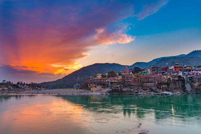 Dusk time at Rishikesh, holy town and travel destination in India. Colorful sky and clouds reflecting over the Ganges River.